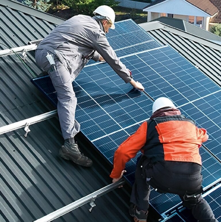 Technicien installant des panneaux photovoltaïques sur le toit d'une maison