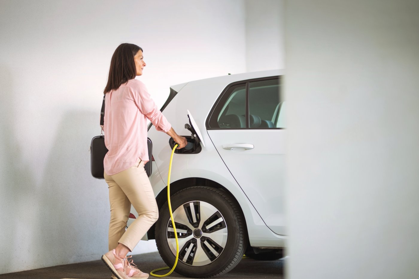 Woman charging a electric car at a garage
