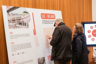 participant devant un stand d'informations SIE lors de la conférence publique des SIE « L'avenir du solaire en Suisse »